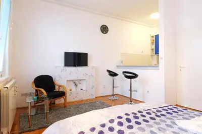 a bedroom with a bed and a chair and a fireplace at Apartment Aska in Belgrade