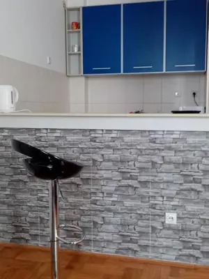 a kitchen with a counter with blue cabinets and a stool at Apartment Aska in Belgrade