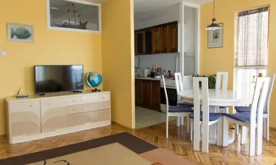 a kitchen and dining room with a table and a tv at Sunny Apartment in Belgrade
