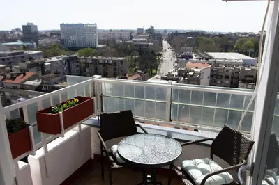 a balcony with a table and chairs and a view of a city at Sunny Apartment in Belgrade