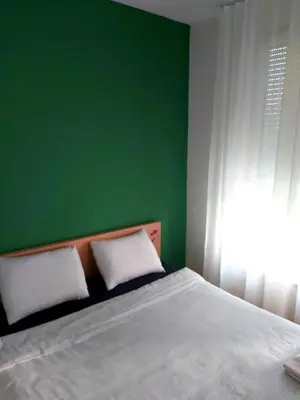 a bedroom with a green wall and a bed with two pillows at Apartman Green relax Belville in Belgrade