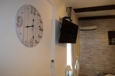 a clock hanging on a wall next to a television at Saramala Apartment in Belgrade