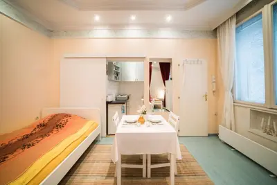 a bedroom with a table and a bed and a kitchen at White Pearl Apartment in Belgrade