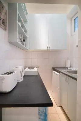 a kitchen with white cabinets and a black counter top at White Pearl Apartment in Belgrade