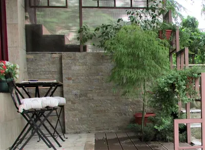 a patio with a brick wall and a chair and a tree at Apartment B&S in Belgrade