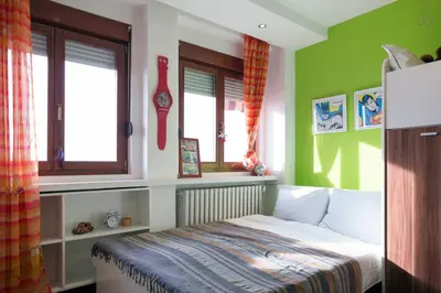 a bedroom with a bed with green walls and windows at Roof Penthouse 15th Floor in Belgrade