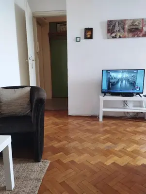 a living room with a flat screen tv and a chair at Apartman Centar Beograd in Belgrade