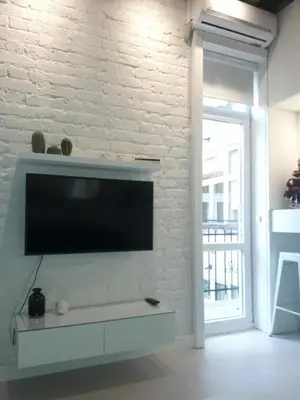 a living room with a tv on a white brick wall at Momo Apartment in Belgrade