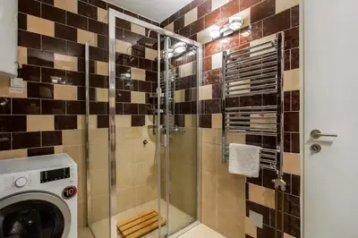 a bathroom with a shower with a washing machine at Belgrade Sky Apartment in Belgrade