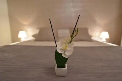 a vase with flowers in it sitting on a bed at Apartman Centar Bg in Belgrade
