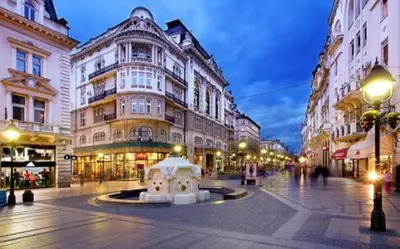 a city street with buildings and a fountain in the middle at Apartment Bourgeois in Belgrade