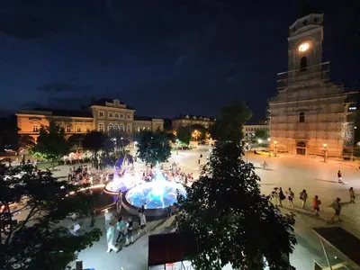 a group of people walking around a plaza at night at Prenociste Nikolas Grand in Smederevo