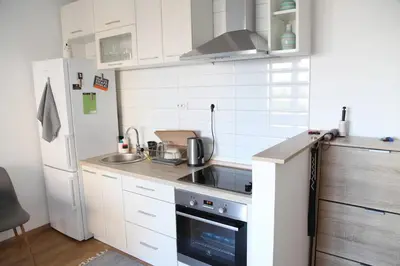 a small kitchen with white cabinets and a refrigerator at Bardolino Apartment in Belgrade