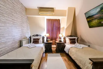 two beds in a room with a brick wall at Vila Hit in Ruma