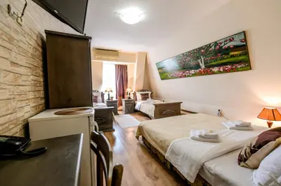 a bedroom with two beds and a living room at Vila Hit in Ruma