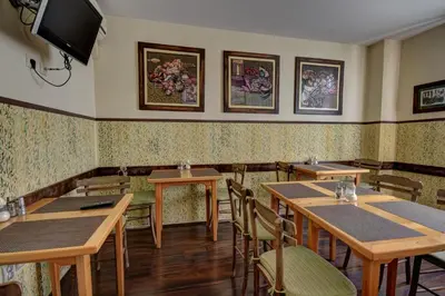 a restaurant with tables and chairs and a tv on the wall at Vila Hit in Ruma