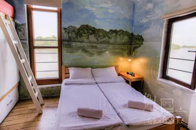 a bedroom with a bed and a painting on the wall at ArkaBarka Floating Hostel in Belgrade