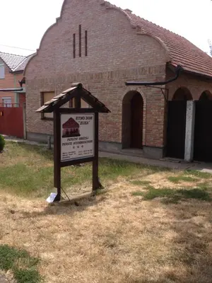 a sign in the grass in front of a building at etno dom 