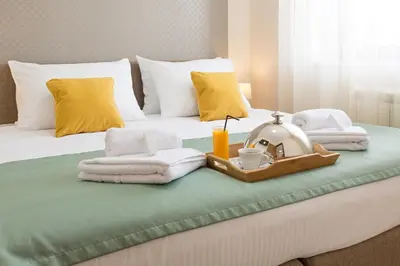 a bed with towels and a tray with a tea set on it at Prime Hotel Apartmani in Belgrade