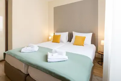 two beds in a hotel room with towels on them at Prime Hotel Apartmani in Belgrade