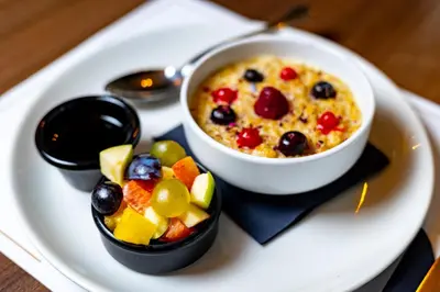 a plate of food with a bowl of oatmeal and fruit at MARK Hotel in Belgrade