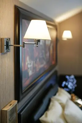 a lamp on a wall next to a bed in a room at Lux apartmani Beograd in Belgrade