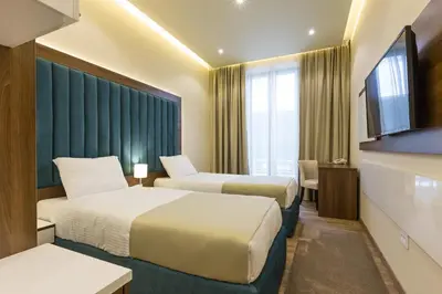 a hotel room with two beds and a flat screen tv at Marquise Hotel Garni in Belgrade