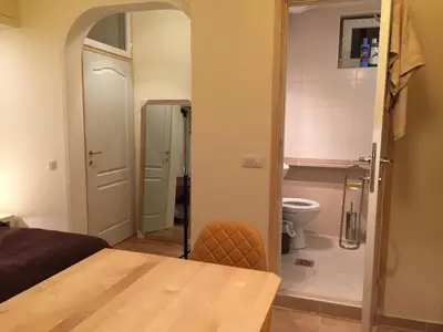 a room with a table and a bathroom with a toilet at Crown Street Garden Studio in Belgrade