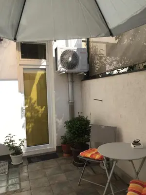 a patio with a table and an umbrella and a fan at Crown Street Garden Studio in Belgrade