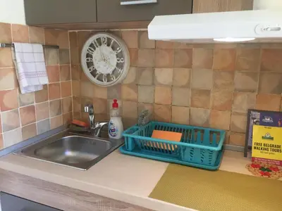 a kitchen counter with a sink and a clock on the wall at Crown Street Garden Studio in Belgrade