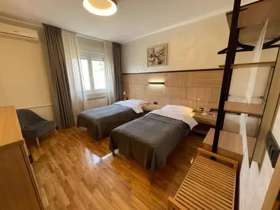 a room with two beds and a desk at Booky Apartment in Belgrade