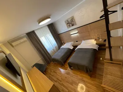 a hotel room with two beds and a television at Booky Apartment in Belgrade
