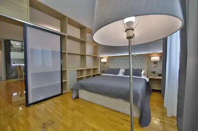 a bedroom with a bed and a floor lamp at Booky Apartment in Belgrade