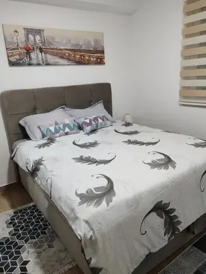a bed with a gray and white comforter on it at Apartment Violet in Belgrade