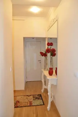 a hallway with a table with red flowers in a mirror at Apartment ON TOP 23 in Belgrade