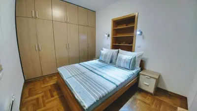 a small bedroom with a bed and wooden cabinets at Apartment Harmonija in Belgrade