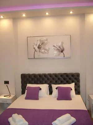 a bedroom with a large bed with purple and white pillows at Rose Lux in Belgrade