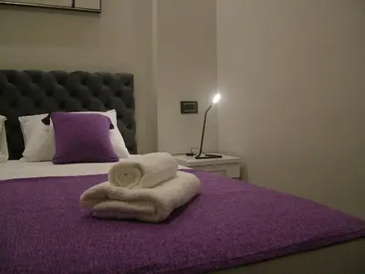 a bed with a purple blanket with a towel on it at Rose Lux in Belgrade