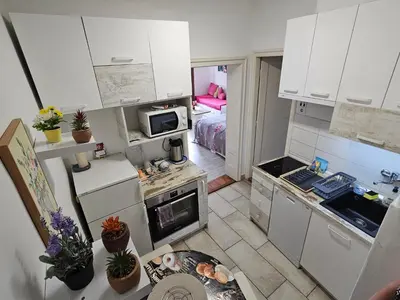 a small kitchen with white cabinets and a bed at Matea apartman in Belgrade