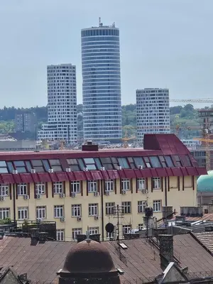 a building with a red roof in front of tall buildings at Matea apartman in Belgrade