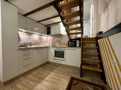 a kitchen with white cabinets and a spiral staircase at Cherrycity apartments in Belgrade