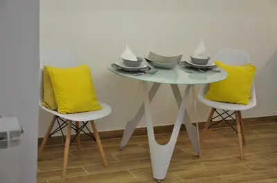 a table with yellow pillows and a table with two chairs at M48 apartments in Belgrade