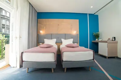 two beds in a room with blue walls at City Nest Modern & Cozy Suites in Belgrade