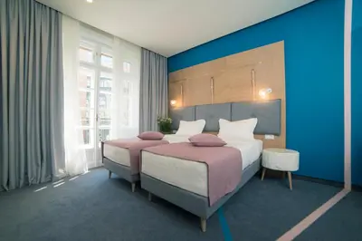 a bedroom with two beds and a blue wall at City Nest Modern & Cozy Suites in Belgrade