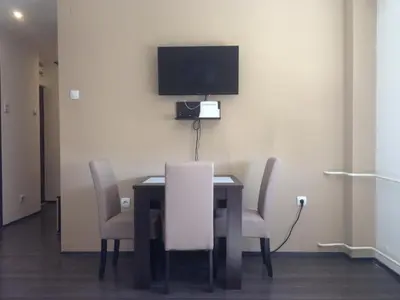 a dining room table with chairs and a tv on the wall at Markoni in Pančevo