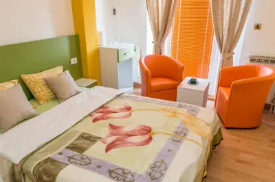 a bedroom with a large bed with two orange chairs at Kalanj Apartmani I Sobe in Belgrade