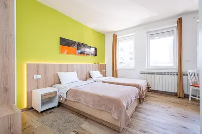 two beds in a room with yellow walls at Kalanj Apartmani I Sobe in Belgrade