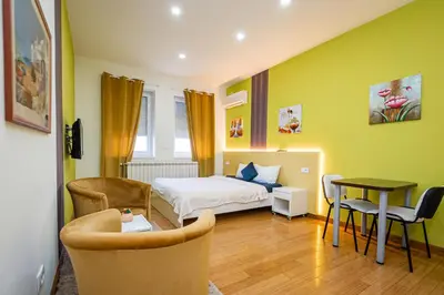 a bedroom with a bed and a table and chairs at Kalanj Apartmani I Sobe in Belgrade