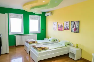 two beds in a room with green walls at Kalanj Apartmani I Sobe in Belgrade