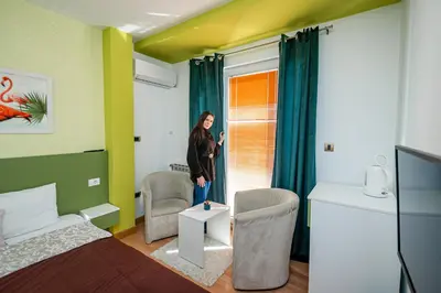a woman standing in a bedroom with a window at Kalanj Apartmani I Sobe in Belgrade